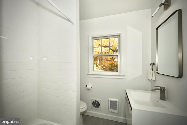 bathroom with heating unit, vanity, hardwood / wood-style flooring, and toilet