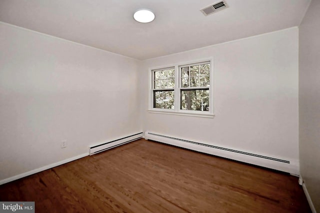 unfurnished room with a baseboard heating unit and dark wood-type flooring