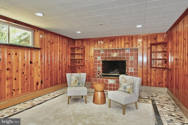 sitting room featuring crown molding, wood walls, carpet flooring, and a tile fireplace