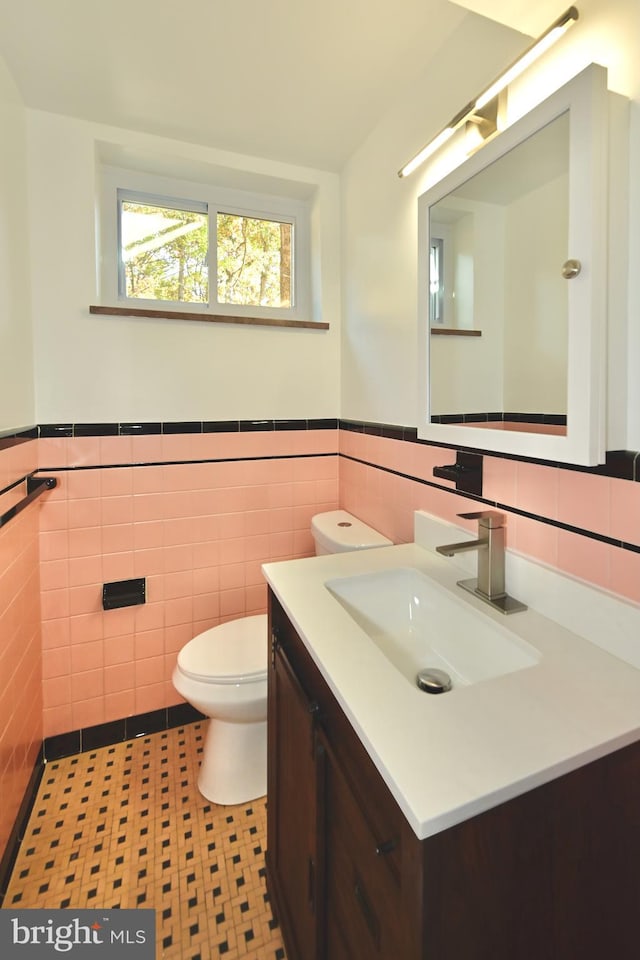 bathroom with vanity, toilet, tile walls, and tile patterned flooring