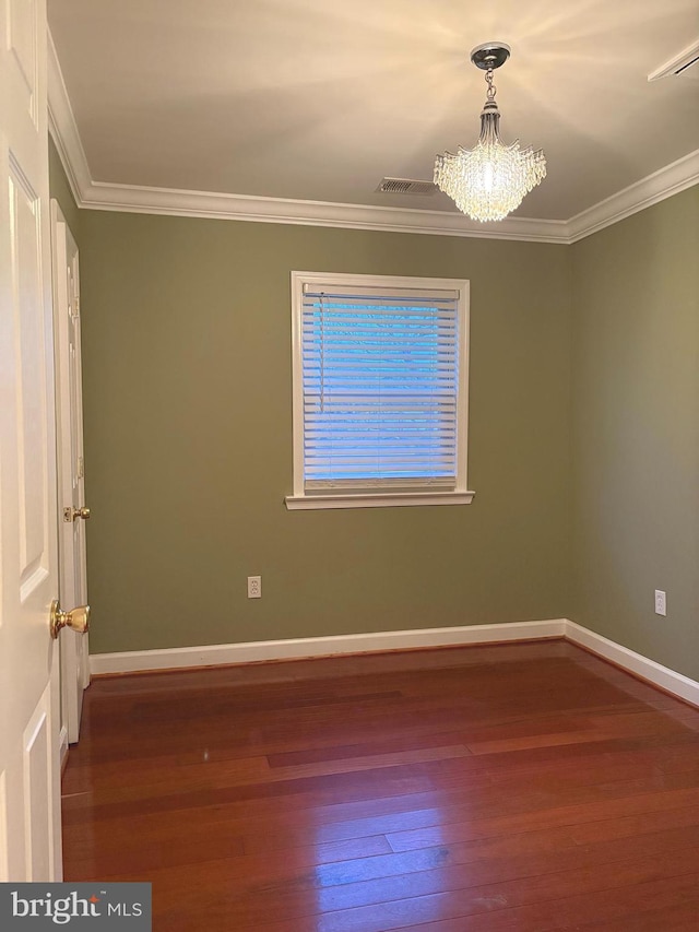 unfurnished room featuring hardwood / wood-style flooring, crown molding, and an inviting chandelier