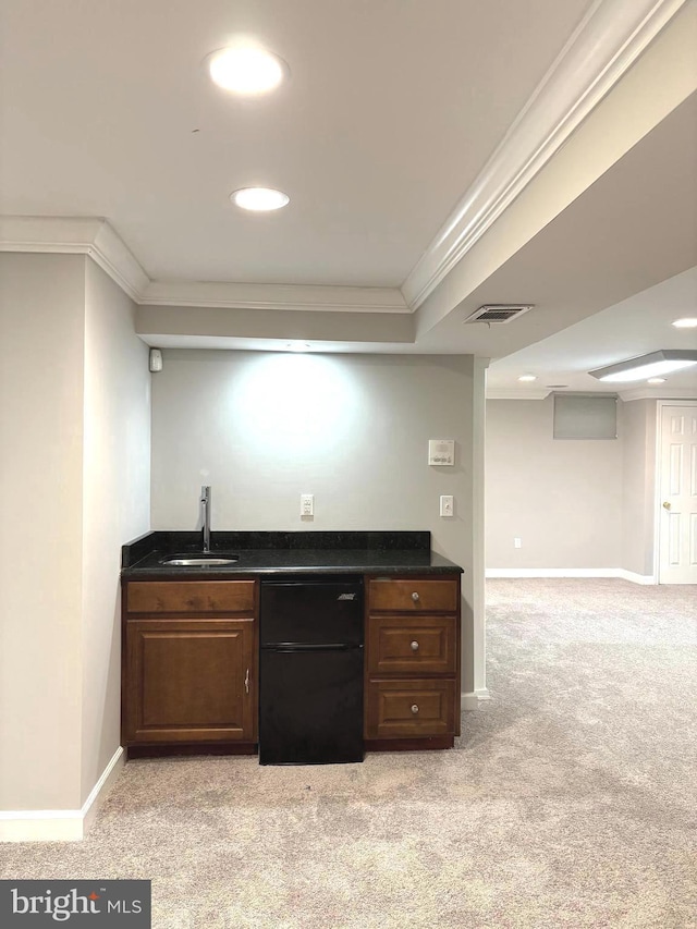 bar with sink, crown molding, dark brown cabinets, fridge, and light colored carpet