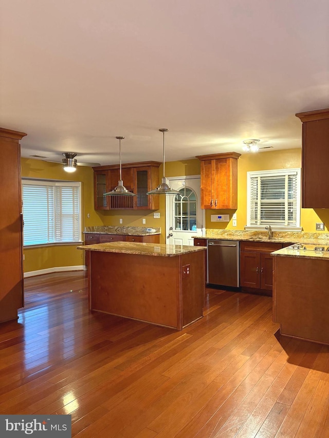 kitchen with dark wood-type flooring, stainless steel dishwasher, a center island, and hanging light fixtures