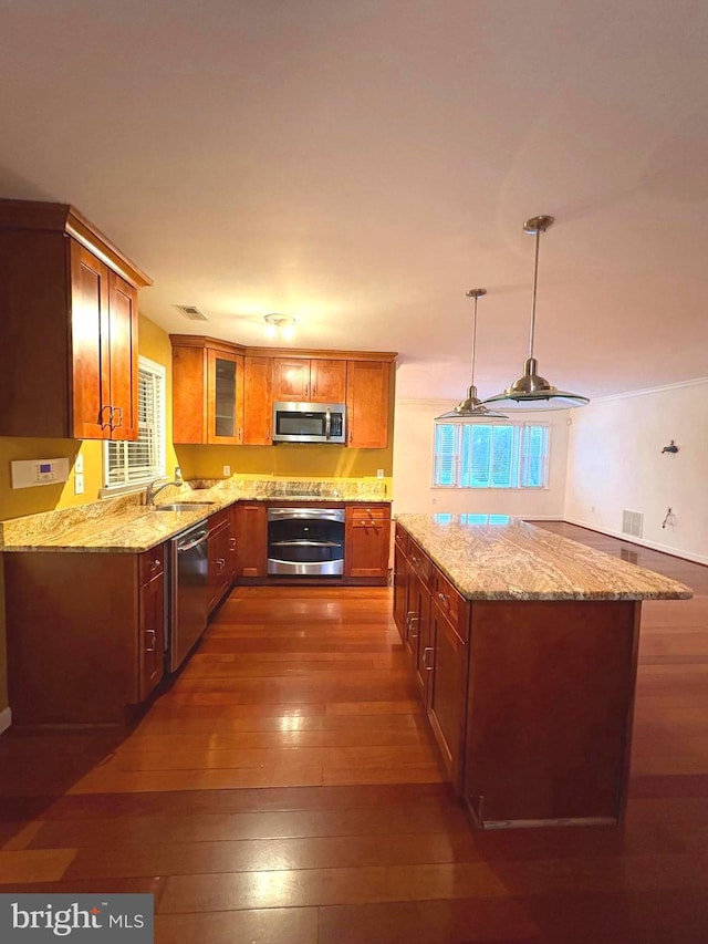 kitchen featuring sink, decorative light fixtures, appliances with stainless steel finishes, dark hardwood / wood-style flooring, and light stone countertops