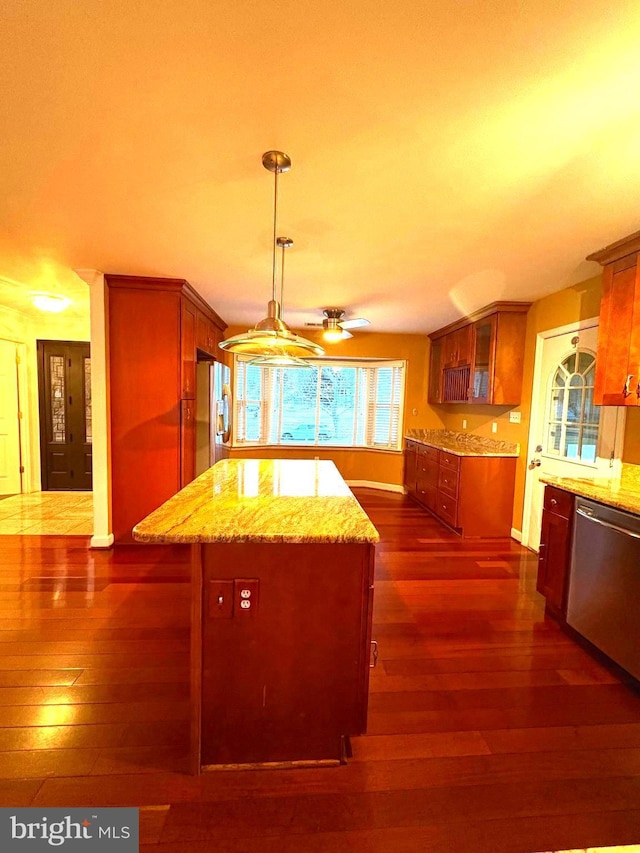 kitchen with pendant lighting, appliances with stainless steel finishes, dark hardwood / wood-style floors, light stone countertops, and a kitchen island