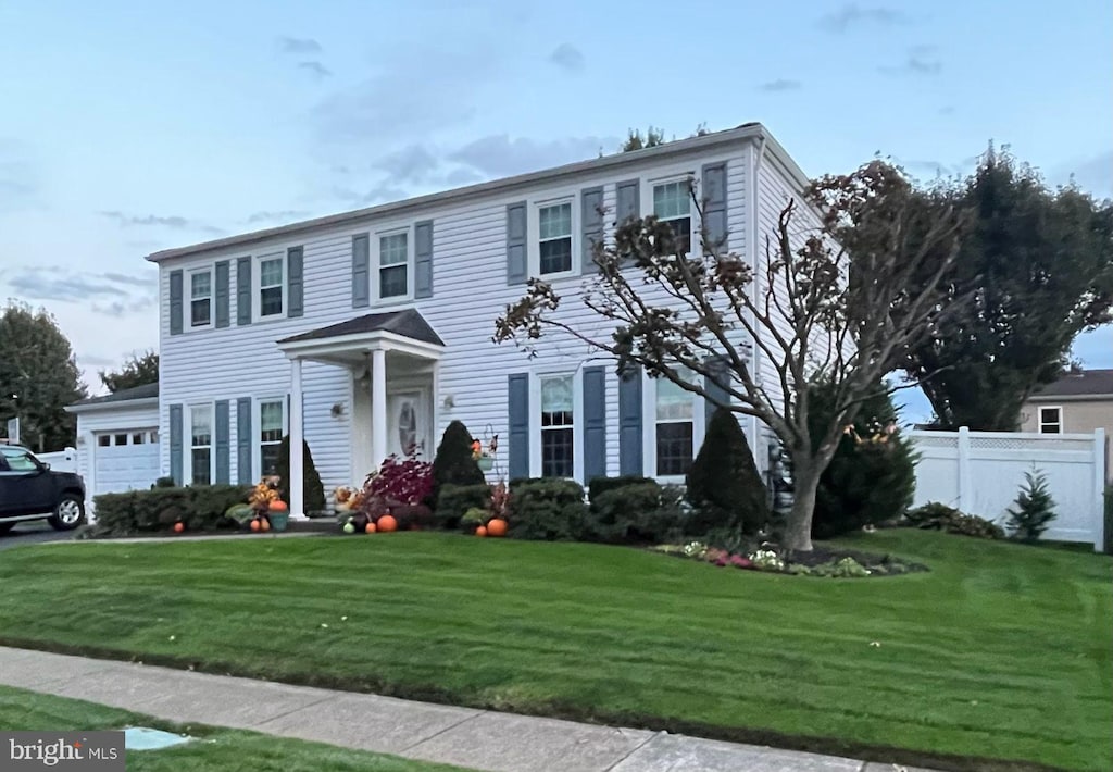 colonial inspired home featuring a front yard and a garage