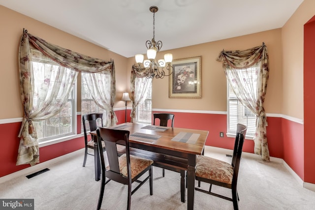 dining area featuring a chandelier, light colored carpet, and a wealth of natural light