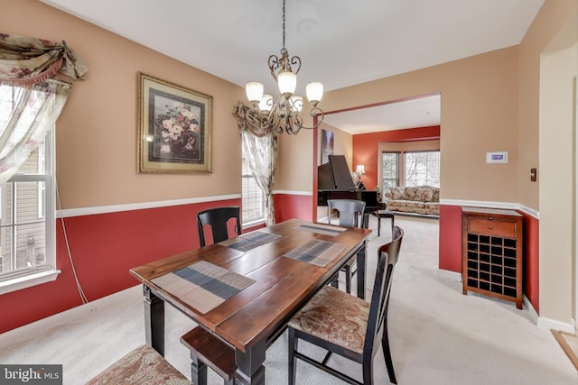 carpeted dining area with a notable chandelier