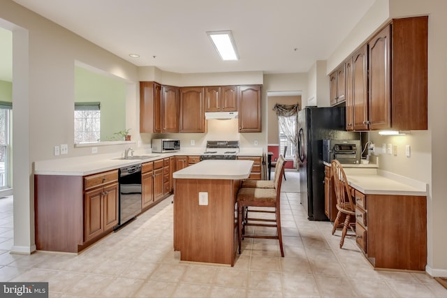 kitchen featuring sink, black appliances, light tile patterned floors, a center island, and a breakfast bar area