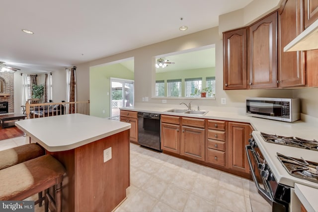 kitchen with sink, ceiling fan, black dishwasher, range with gas stovetop, and a kitchen bar