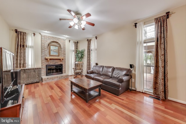 living room with a brick fireplace, ceiling fan, and hardwood / wood-style flooring