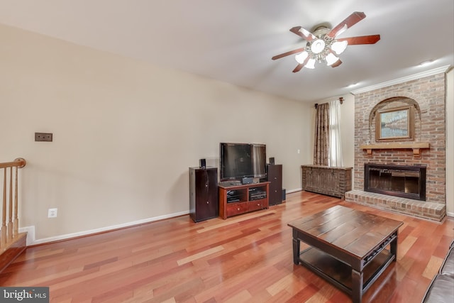 living room featuring ceiling fan, a fireplace, crown molding, and hardwood / wood-style flooring