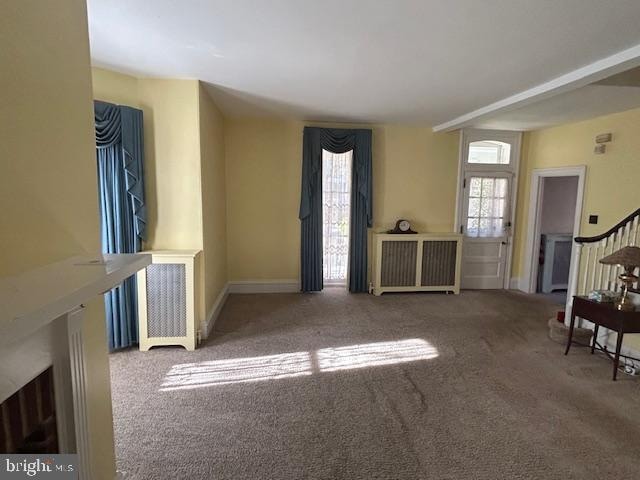 unfurnished living room featuring radiator heating unit and carpet floors