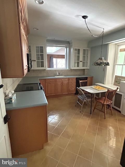 kitchen featuring black appliances, light tile patterned floors, hanging light fixtures, sink, and decorative backsplash