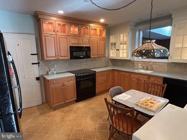 kitchen featuring pendant lighting, sink, black appliances, and decorative backsplash