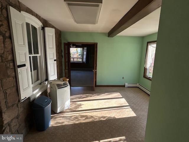 carpeted empty room featuring baseboard heating and beamed ceiling