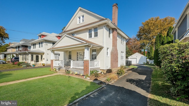 view of front facade with a garage, covered porch, an outdoor structure, and a front yard