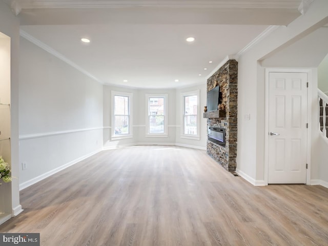 unfurnished living room with light hardwood / wood-style floors, a stone fireplace, and crown molding