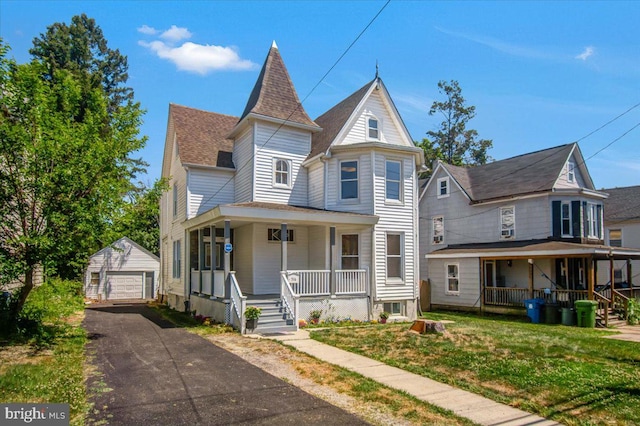 victorian home featuring covered porch, a garage, a front lawn, and an outdoor structure