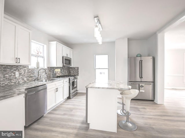 kitchen featuring light stone countertops, sink, a center island, white cabinets, and appliances with stainless steel finishes