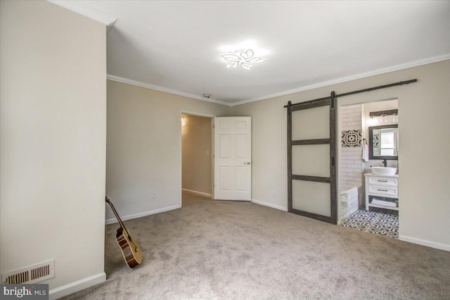 unfurnished bedroom with carpet, a barn door, sink, and crown molding