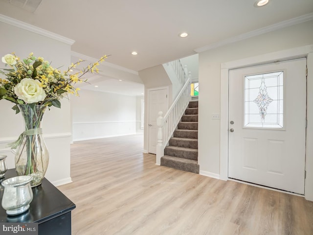 foyer entrance with ornamental molding and light hardwood / wood-style flooring