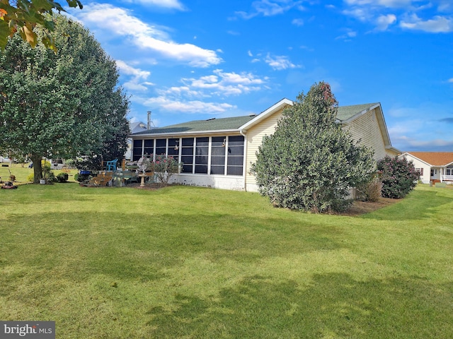 rear view of house with a lawn and a sunroom