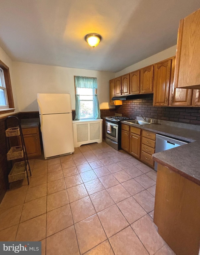 kitchen featuring gas stove, decorative backsplash, light tile patterned floors, and white refrigerator