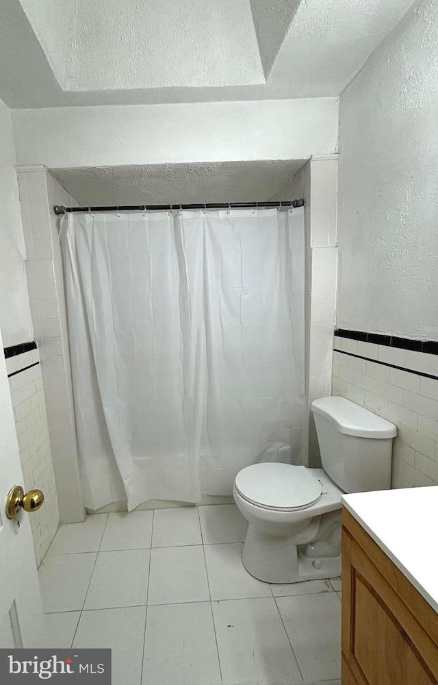 bathroom featuring toilet, tile patterned floors, tile walls, a shower with curtain, and vanity