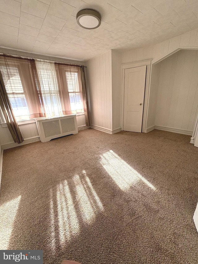 carpeted empty room with a healthy amount of sunlight and radiator