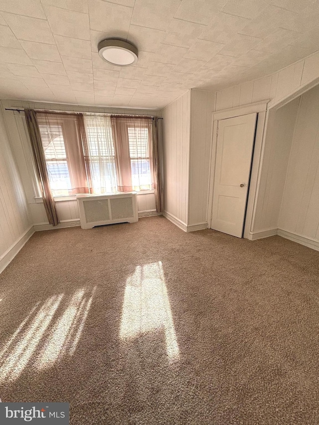 carpeted spare room with radiator heating unit