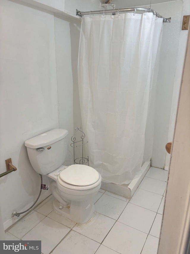 bathroom with toilet, curtained shower, and tile patterned flooring