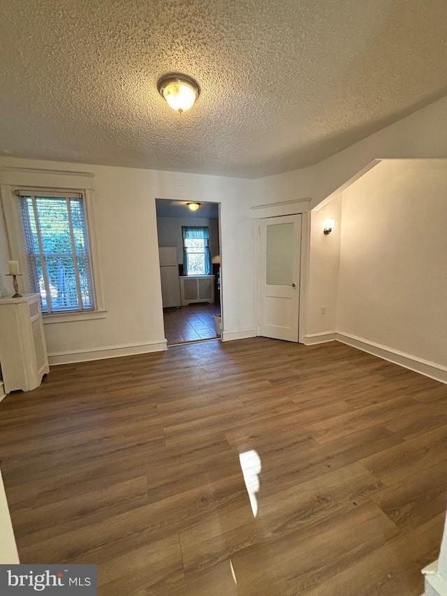 unfurnished room featuring a textured ceiling and dark hardwood / wood-style flooring