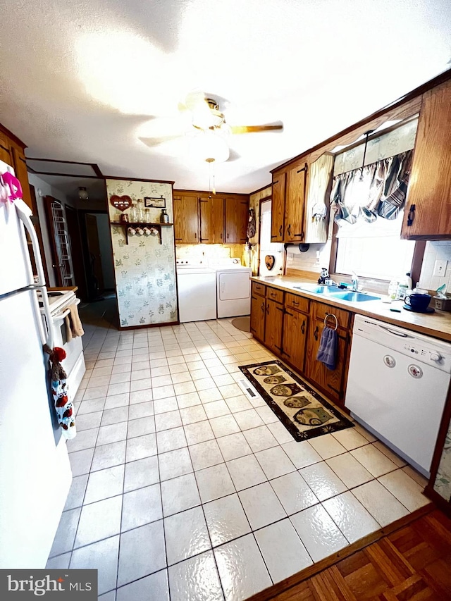 kitchen featuring light tile patterned floors, sink, washing machine and clothes dryer, white appliances, and ceiling fan