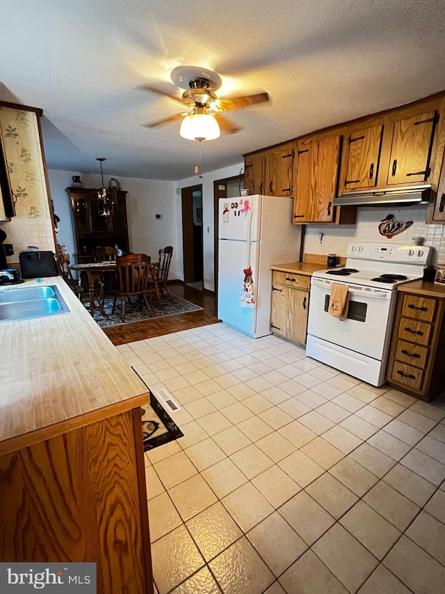 kitchen with light tile patterned flooring, a textured ceiling, sink, white appliances, and ceiling fan