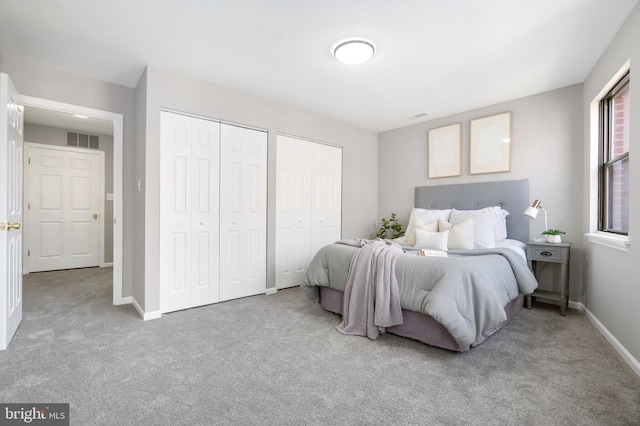 bedroom featuring light carpet and two closets