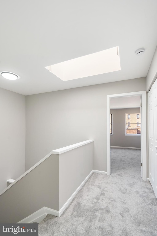 hall featuring a skylight and light colored carpet