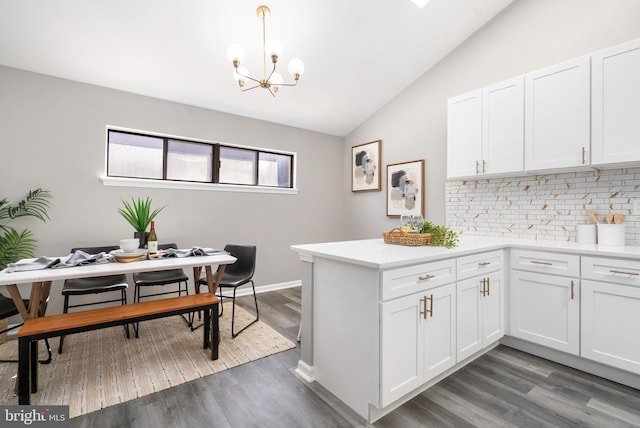 kitchen with white cabinetry, dark wood-type flooring, hanging light fixtures, and vaulted ceiling