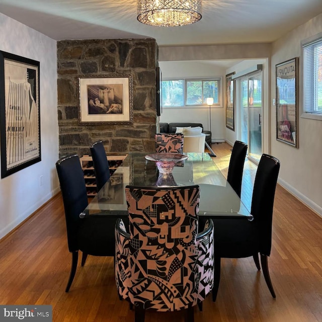 dining space with hardwood / wood-style floors, a healthy amount of sunlight, and an inviting chandelier