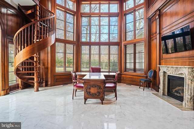 dining space featuring a premium fireplace, wood walls, and a high ceiling