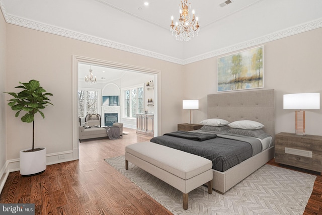 bedroom with light hardwood / wood-style floors, an inviting chandelier, and crown molding