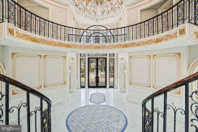 foyer entrance featuring french doors, crown molding, a notable chandelier, and a high ceiling