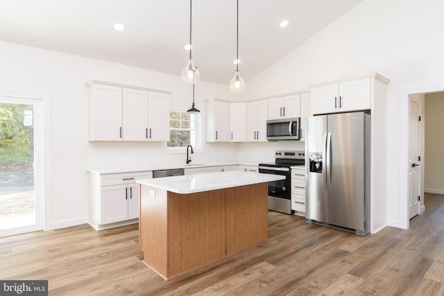 kitchen featuring appliances with stainless steel finishes, white cabinets, a center island, and light wood-type flooring