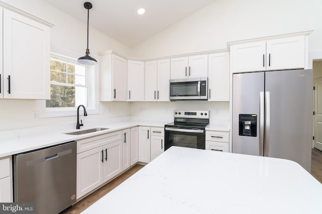 kitchen with stainless steel appliances, sink, vaulted ceiling, decorative light fixtures, and white cabinets