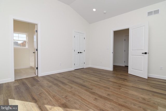 unfurnished bedroom featuring dark hardwood / wood-style flooring, lofted ceiling, and ensuite bath