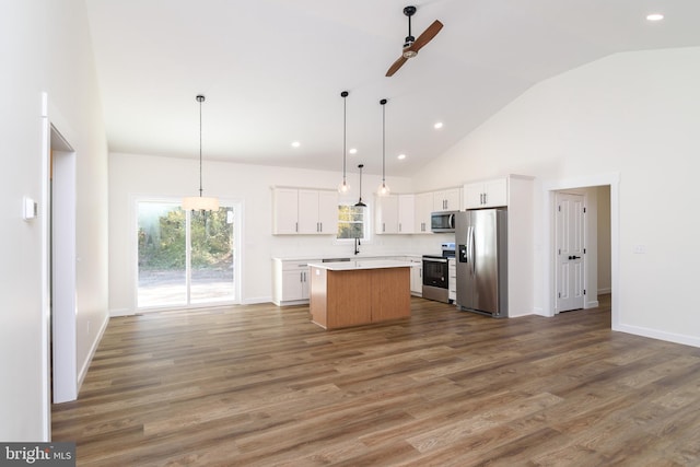 kitchen with a center island, white cabinets, decorative light fixtures, and stainless steel appliances