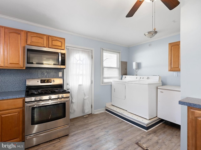 kitchen with appliances with stainless steel finishes, ornamental molding, hardwood / wood-style flooring, and washing machine and clothes dryer