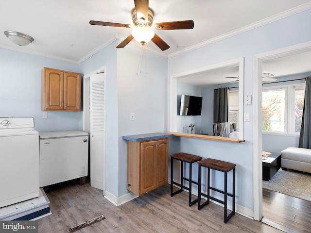 kitchen with washer / dryer, ornamental molding, and hardwood / wood-style floors