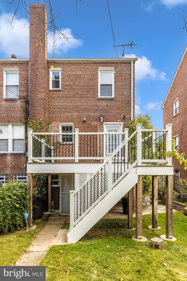 back of property featuring a yard and a wooden deck