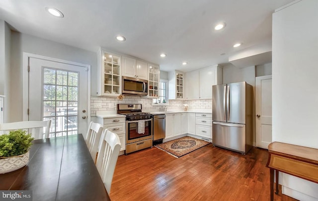 kitchen with stainless steel appliances, decorative backsplash, dark hardwood / wood-style flooring, and white cabinets